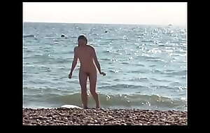 Candid. UK Woman dressed/ undressed on nudist coast