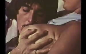 A mustachioed gay blade with long sideburns caresses an experienced comme ci with huge buckets in a 70s video