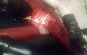 UrsulaTS cumming in a condom wearing shiny red bodysuit