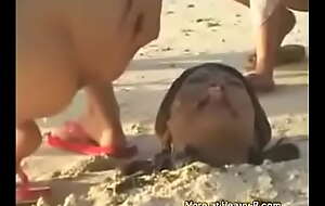 Un groupe de filles asiatique chient sur une asiatique coincé dans le sable